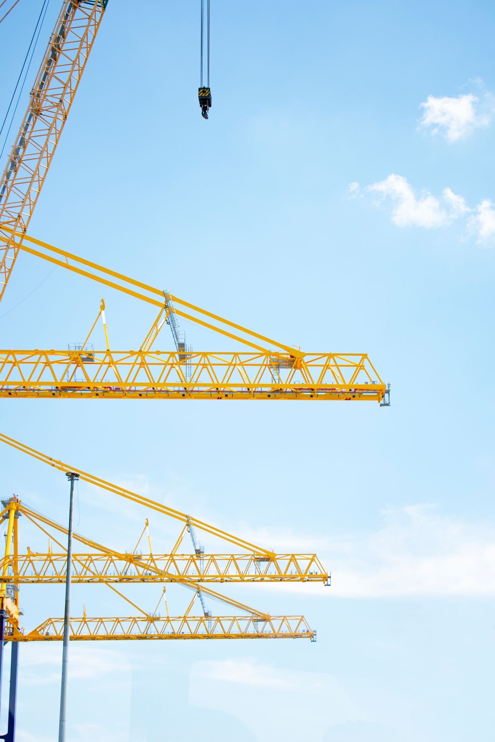 Yellow tower cranes at a construction site against a blue sky