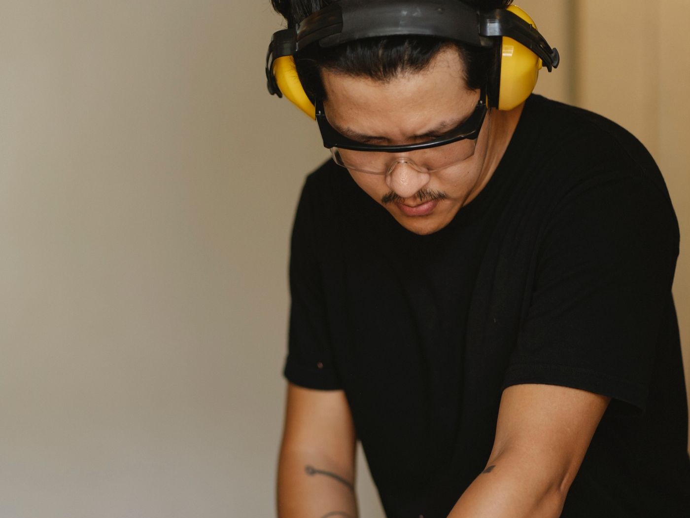 Joiner wearing ear defenders and safety glasses shaping a wooden block on a jointer