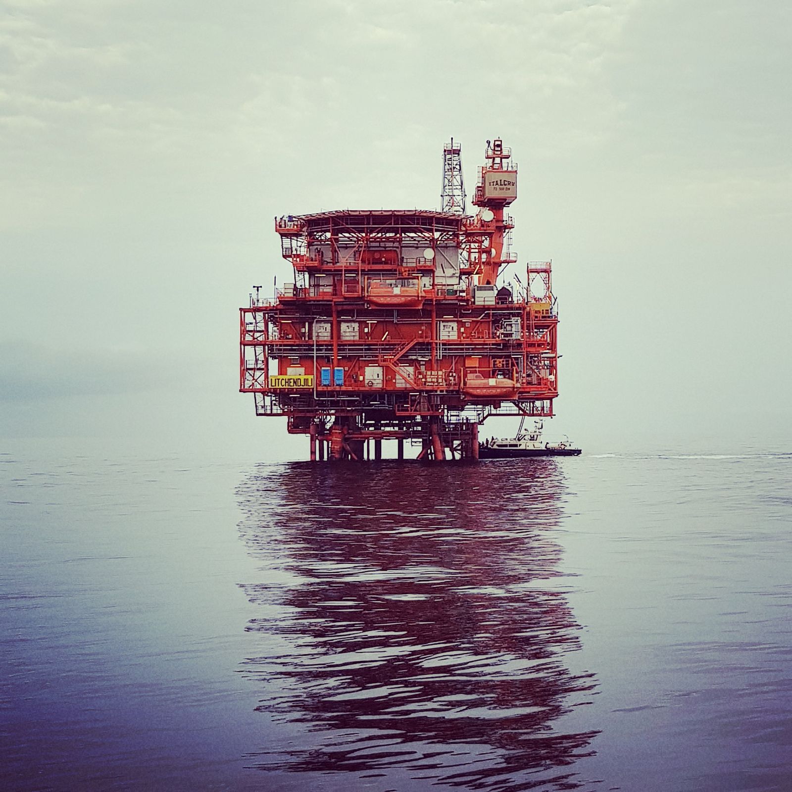 Offshore oil platform reflecting on calm ocean water