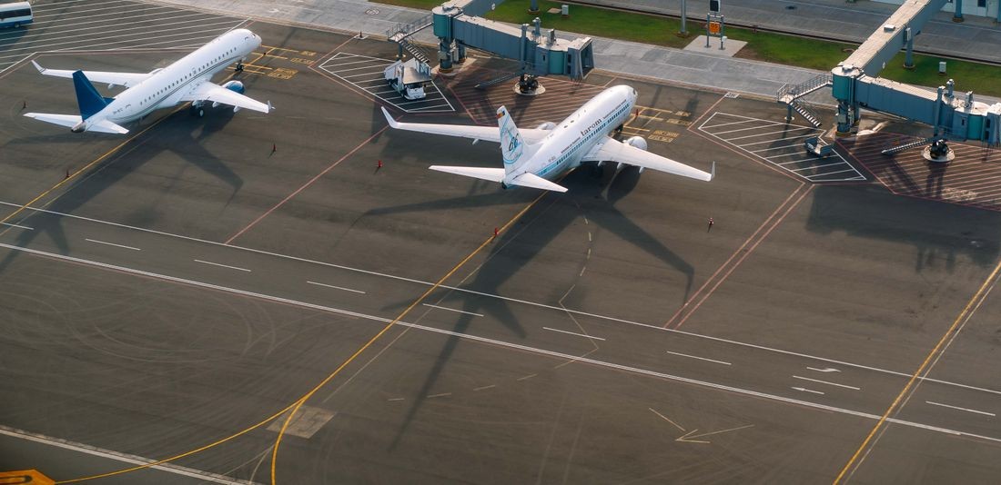 Aerial view of aircraft parked at jet bridges beside an airport terminal