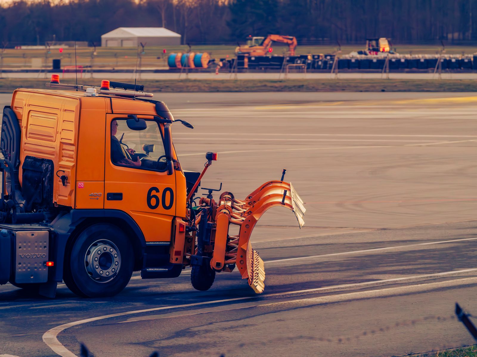 Airport ground maintenance vehicle on the tarmac at sunset