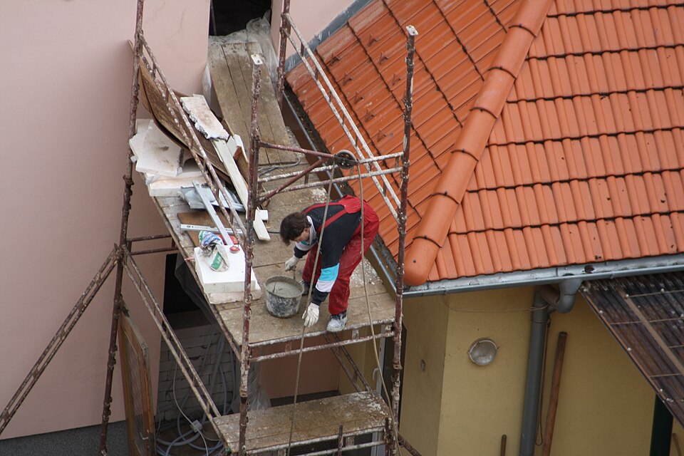 Worker performing exterior building work from scaffolding