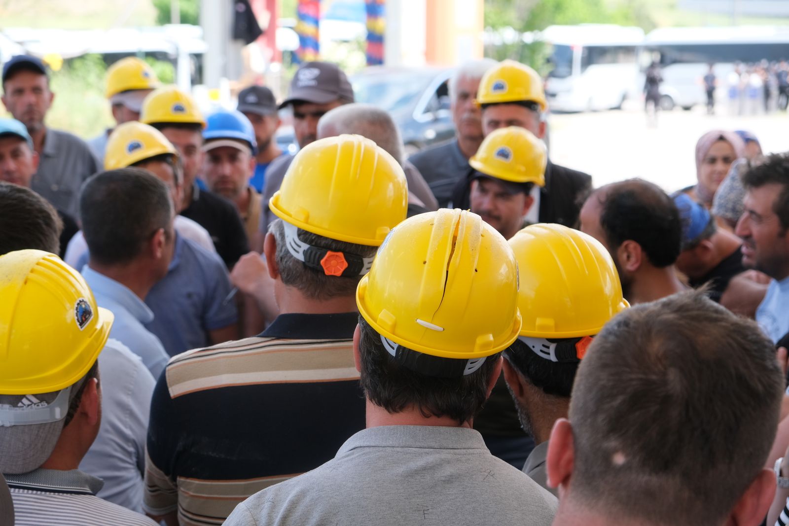 A gathering of construction workers in yellow hard hats discussing outdoors