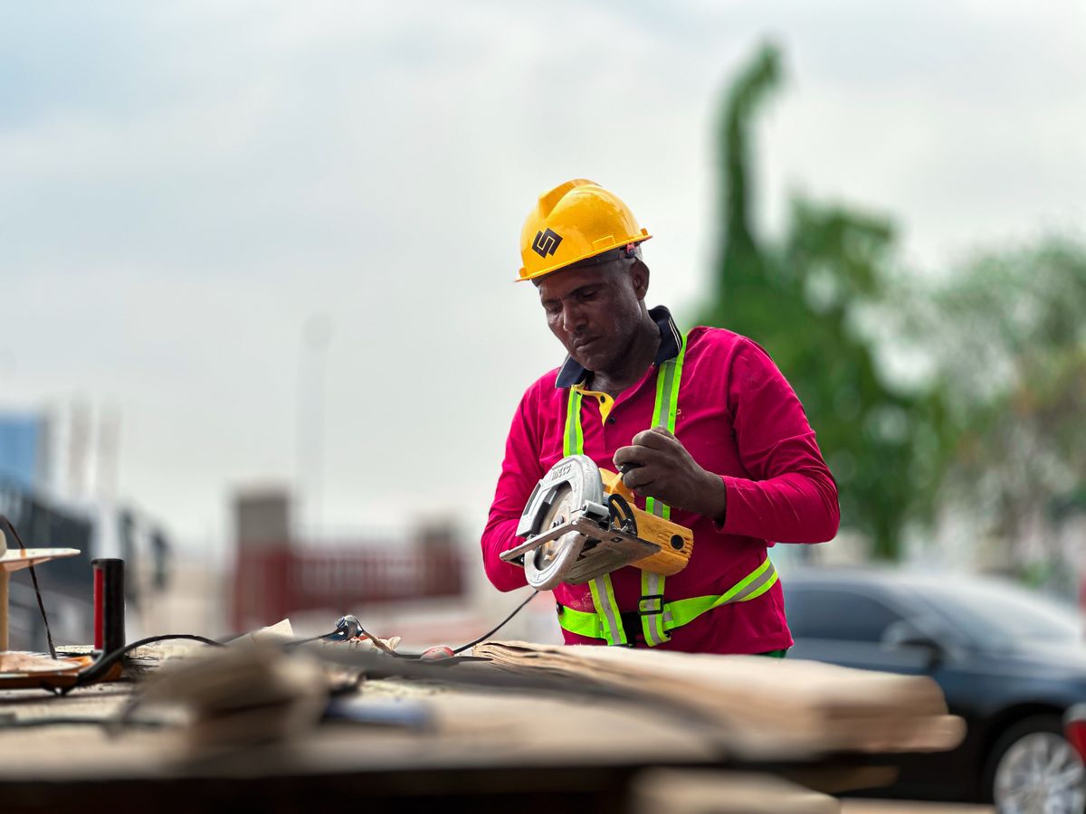 Carpenter in a hard hat and hi-vis harness using a circular saw